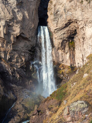 Scenic autumn landscape with vertical big Sultan waterfall at mountain top in sunshine in the Jila-Su tract. Kabardino-Balkaria. Russia, Caucasus. High falling water in Northern Elbrus region.