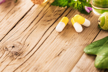 Capsules and healthy oils on wooden background with copy space. Alternative medicine concept