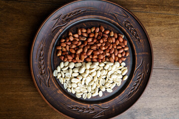 Raw peanuts in a clay bowl. Cajour and shelled beans