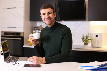 Man drinking a cup of coffee while working from home 