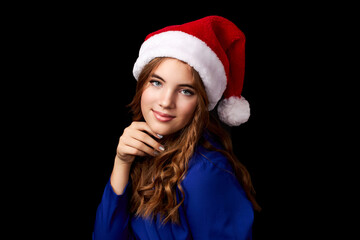 caucasian girl with long hair in blue dress wearing santa claus hat isolated on black background