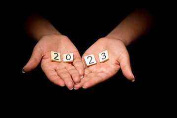 Hands of young female woman with tokens forming the number 2023