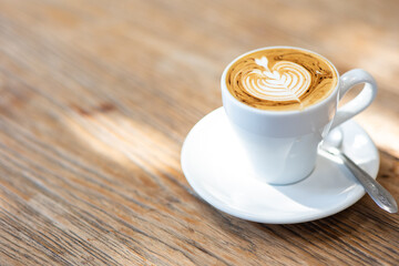 Cup of latte art or cappuccino with foam, coffee cup on table in cafe.