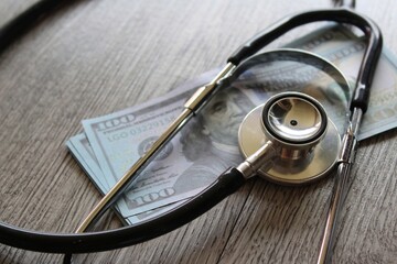 Stethoscope and money on wooden table. Healthcare, medical treatment cost and medicine concept.