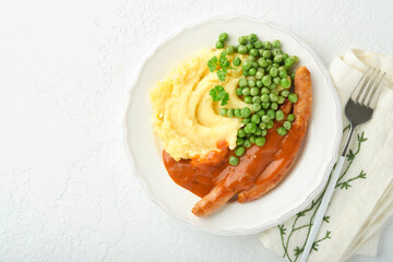 Bangers and mash. Grilled sausages with mash potato and green pea on white plate on light background. Traditional dish of Great Britain and Ireland. BBQ beef sausages. Top view.