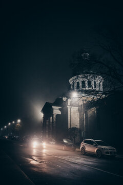 Car driving through a city street on a foggy autumn night.