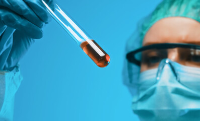 Woman in goggles and mask working with test tubes in laboratory.