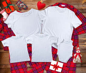 Blank white t-shirts for the whole family on the background of bright pajamas on a wooden...