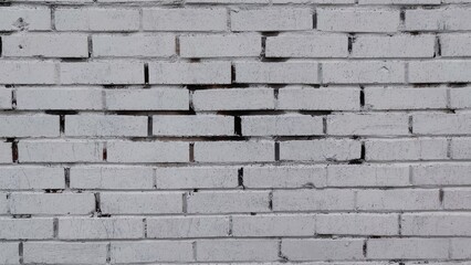 Light smooth surface of a brick wall. The flat surface of a brick wall of identical blocks with a mortar between them. The wall is painted with white paint, there is no paint in some of the seams.