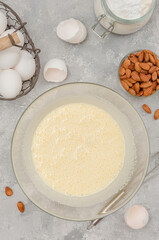 Recipe step by step. The process of making Italian cantucini cookies. Whipped eggs with sugar in a bowl on a gray concrete background. Top view.