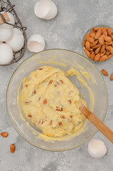 Recipe step by step. The process of making Italian cantucini cookies. Finished dough with almond in a bowl on a gray concrete background. Top view.