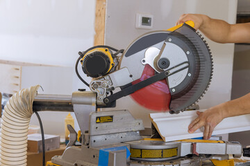 On circular saw, construction worker cuts wood moldings boards as part of finishing work