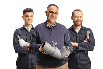 Portrait of a mature man holding a plastic pipe and plumbers standing behind