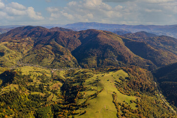 Beautiful autumn forest in the Carpathian mountains with cloudy sky on a autumn day on the Synevyr Pass ridge and blue sky background. Ukraine, drone view