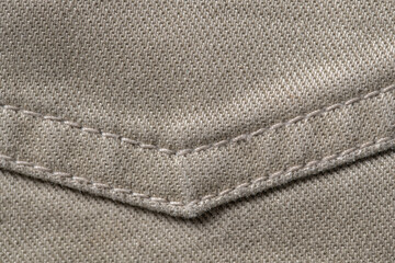 Thread stitching on light denim. Beige jeans fabric background or denim texture. Closeup view