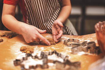girl makes ginger cookies with Christmas cookie forms