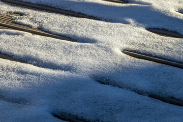 White snow-covered surface. Stones and wood planks covered with fluffy melting snow.