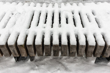 In winter, the bench in the park is covered with snow