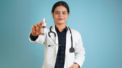 Portrait of a young female doctor holding eyes, ear or nose drop, Cheerful Asian Indian woman...