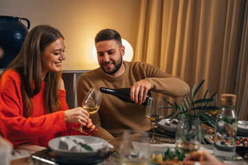 Man pours wine into woman's glass