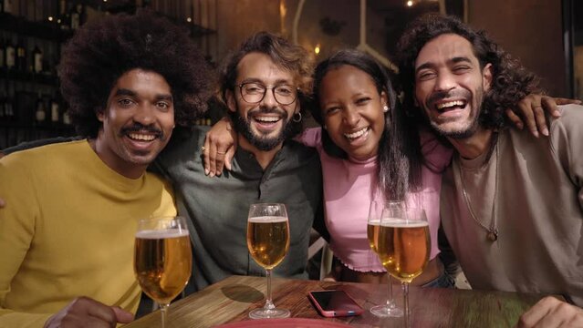Portrait of A group of friends looking at camera in the restaurant bar after work at the pub happy hour. Happy friends having fun together drinking alcohol indoors.