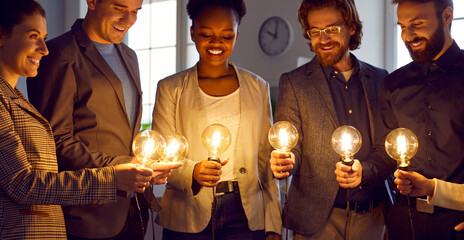 Business people look at bright idea light bulbs. Smart multiracial team share professional...
