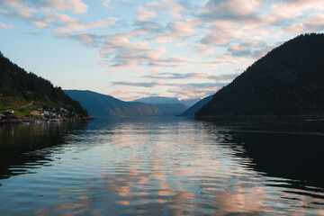 Puffy clouds in pastel orange during sunset at fjord in Norway, Sognefjord 