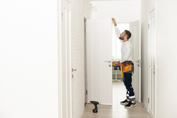 good looking man working as handyman and fixing a door lock in a house entrance