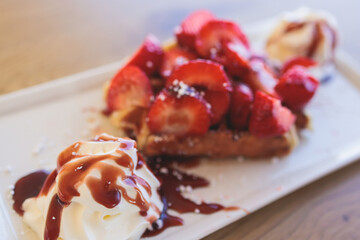 Breakfast with traditional dessert - Belgian waffle with fresh berries, whipped cream and caramel sauce syrup, plate with viennese waffles served on the white plate in a cafe