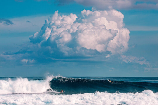 Male surfer on the wave under clouds