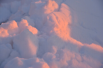 Pink snow winters in the light of the setting sun. Pink and blue winter fluffy snow in winter. A snowdrift in the rays of the setting sun.