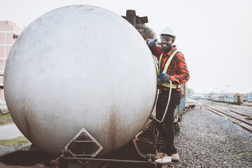 African engineer inspecting oil or fuel tanks transported by train.Engineering and transportation...