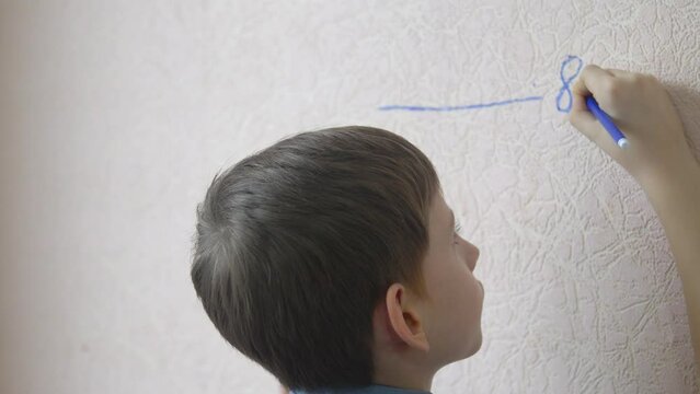 close-up of a caucasian boy draws a mark of 8 years on the wall, the boy has become a year older, measuring the growth of a schoolboy. kid celebrating birthday
