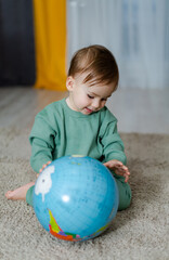 Baby holding a globe in his hands and dreaming about future travels. Child exploring the world. Baby and globe.