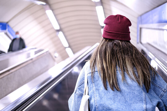 Backwards picture of unrecognizable woman with beanie while using escalators