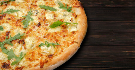 Four cheese pizza quattro fromaggi with arugula leaves on a wooden board on gray concrete horizontal
