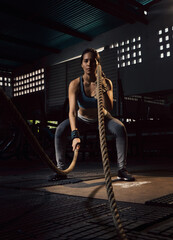 Woman training with battle rope in cross-training gym