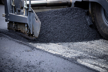 Paver machine adding new asphalt on the road.