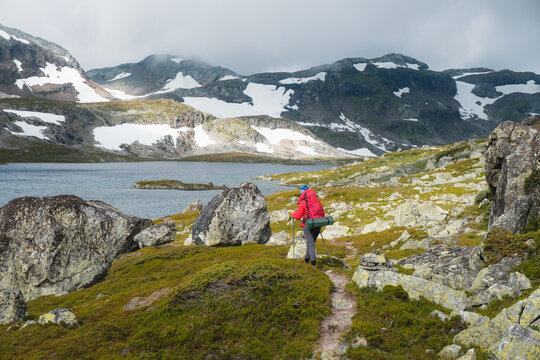 female hiker in red jacket in wild highland in Norway, Hardangervidda nationalpark