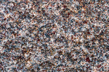 Macro photo a surface of a stone granite rock containing red, blue, black minerals. Texture, background. Closeup top view.