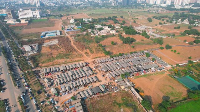 aerial drone decending shot of banjara market in gurgaon delhi showing disorganized temporary tents houses in slums showing this famous handicraft and furniture market surrounded by cars parked on the