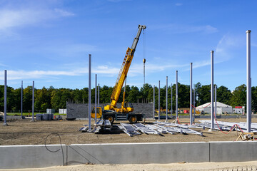 Construction site of a new industrial building with vertical steel columns and a telescopic crane
