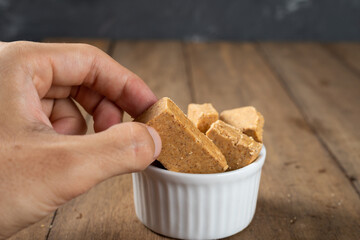 Man's Hand Holding a bowl full of Brazilian Peanut Sweet called Paçoca