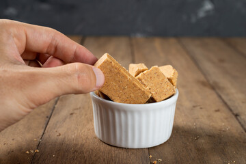 Man's Hand Holding a bowl full of Brazilian Peanut Sweet called Paçoca