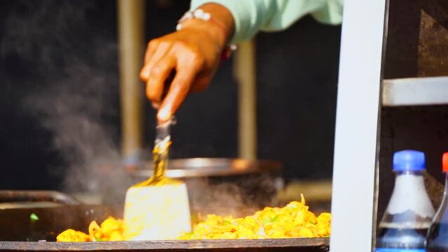 Framed shot of hand frying vegetables, potatoes and rice to make pav bhaji a famous favorite street food of delhi, punjab india served at shops on road side