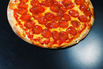 Sliced pizza with sausage, tomato sauce, mozzarella, onion and dough rim, topped with cream cheese on a black background