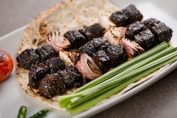 Beef tikka boti seekh kabab with onion and bread served in dish isolated on grey background top view of arabic food