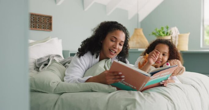 Mother and daughter reading book on a bed in a family home while happy, excited and talking about fantasy story in bedroom. Black woman and girl child together for storytelling, learning and bonding