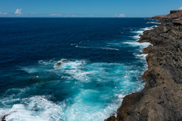 Beautiful landscape with deep blue water. Powerful waves crash against black volcanic rocks on the coast of ´Aguas Verdes, Fuerteventura island. Selective focus, blurred background.
