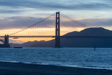 Golden Gate Bridge against a purple pink yellow blue evening sky.  
